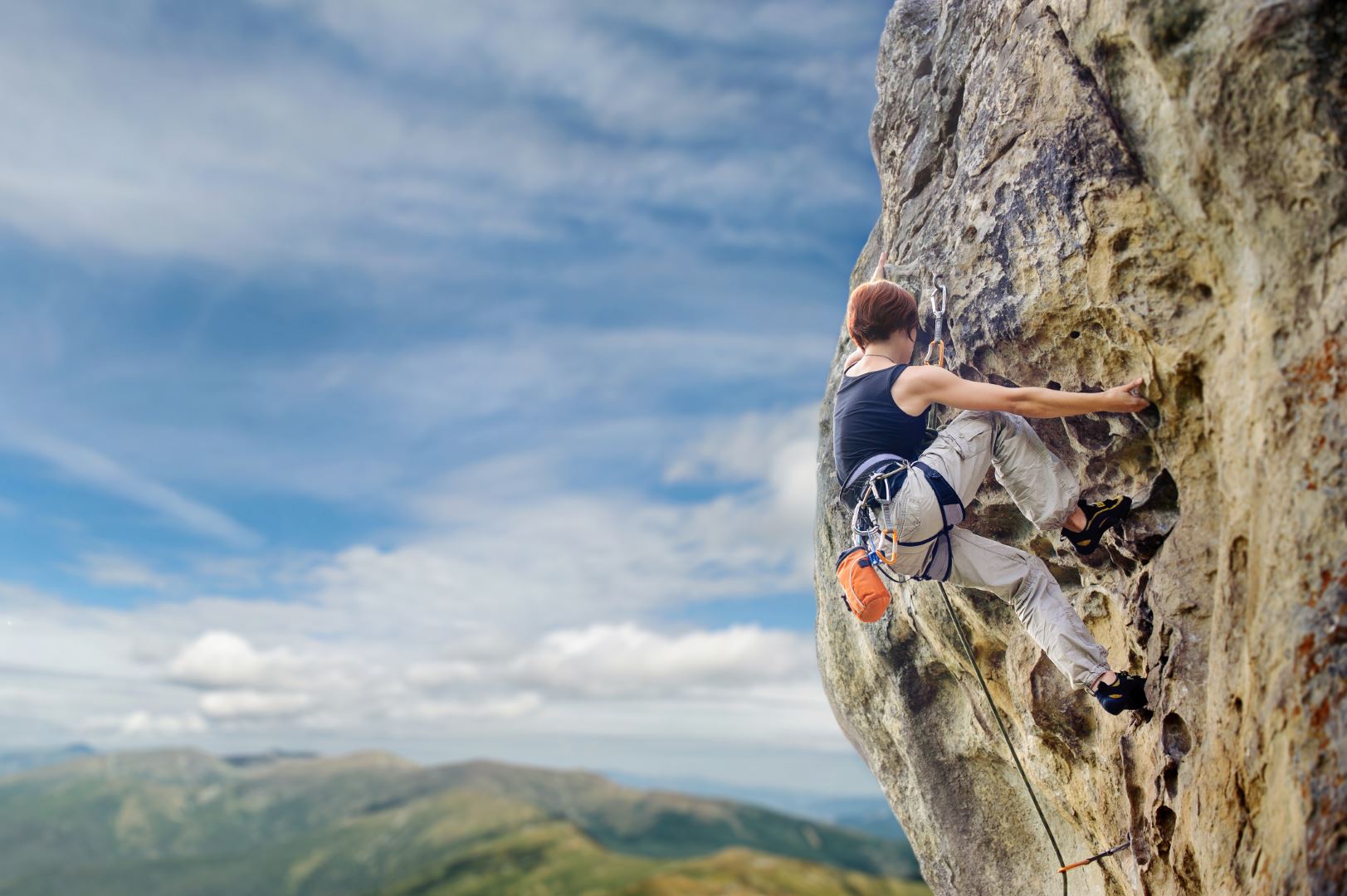 Female rock climber on steep overhanging rock cliff